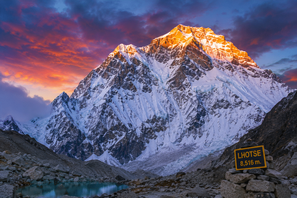Lhotse, the fourth-highest mountain in the world, glowing under a colorful sunset sky with a turquoise alpine lake in the foreground.