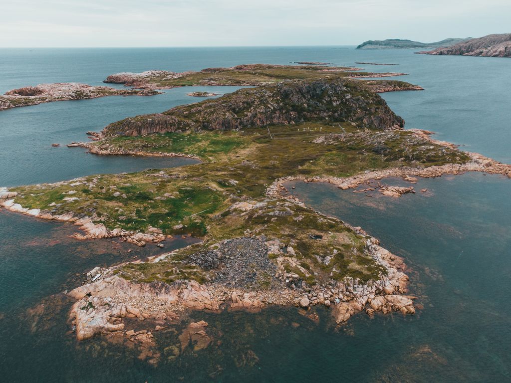 Aerial view of rugged coastal islands with rocky formations and lush green grass.